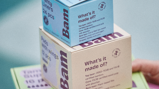 Bam Panty Liners and Pads with Wings boxes stacked, displaying material breakdown: OEKO-TEX and FSC-certified bamboo top layer, FSC-certified wood pulp core, and plant-based back layer.